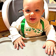 Niko joined the competition — help win amazing prizes! baby, child, high_chair, green, shirt, hands, face, eyes, smile, indoor, kitchen, window, curtains, wooden_cabinet, table, tray, sitting, young_child, clothing, infant