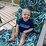 Niko joined the competition — help win amazing prizes! toddler, child, smile, happy, outdoor, deck, chair, patterned_fabric, blue_shirt, shorts, barefoot, railing, sunlight, summer, grass, relaxing, cute, portrait, person, leisure