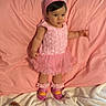 baby, child, pink_dress, headband, standing, playful, tongue_out, blanket, toy, footwear, stride_rite, ruffles, indoors, cute, infant, soft_texture, clothing, portrait, happy, person