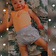 Charlotte joined the competition — help win amazing prizes! baby, infant, bow, orange_clothing, shorts, floral_blanket, smiling, lying_down, cute, child, portrait, indoors, patterned_fabric, happy, person, headband, small_child, skin, baby_girl, background_blur