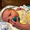 baby, infant, pacifier, blanket, yellow_clothing, giraffe_print, hand, face, couch, newborn, skin, cute, resting, soft, indoor, portrait, closeup, child, young, comfort