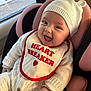 Dua is registered to the contest to win money with this photo: baby, smiling, bib, heart_breaker, knitwear, hat, bear_ears, car_seat, infant, cute, happy, indoors, window, child, portrait, cozy, clothing, seat, person, apparel