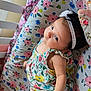 Annabel is registered to the contest to win money with this photo: baby, infant, headband, floral_dress, flower_pattern, cushion, crib, sleepwear, cute, child, portrait, indoors, resting, small_child, soft_lighting, colorful, comfort, young_child, laying_down, adorable