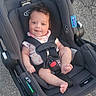 Magnolia is registered to the contest to win money with this photo: baby, car_seat, infant, smiling, curly_hair, floral_onesie, straps, outdoors, pavement, cute, happy, child, seatbelt, foot, hand, headrest, car_seat_harness, person, toddler, safety