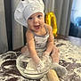 apron, baby, baking, chef_hat, child, cooking, cute, face, flour, fun, glass_bowl, happy, indoor, kitchen, messy, person, playful, rolling_pin, smiling, table