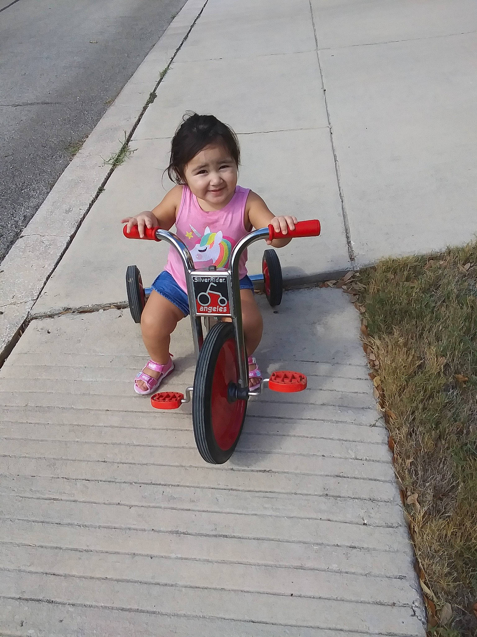 Nairobi is registered to the contest to win money with this photo: baby_toddler_clothing, bicycle_part, bicycle_tire, bicycles_equipment_and_supplies, child, curb, joy, lane, person, play, riding_toy, sandal, sidewalk, sneakers, tar, toddler, toy, tricycle