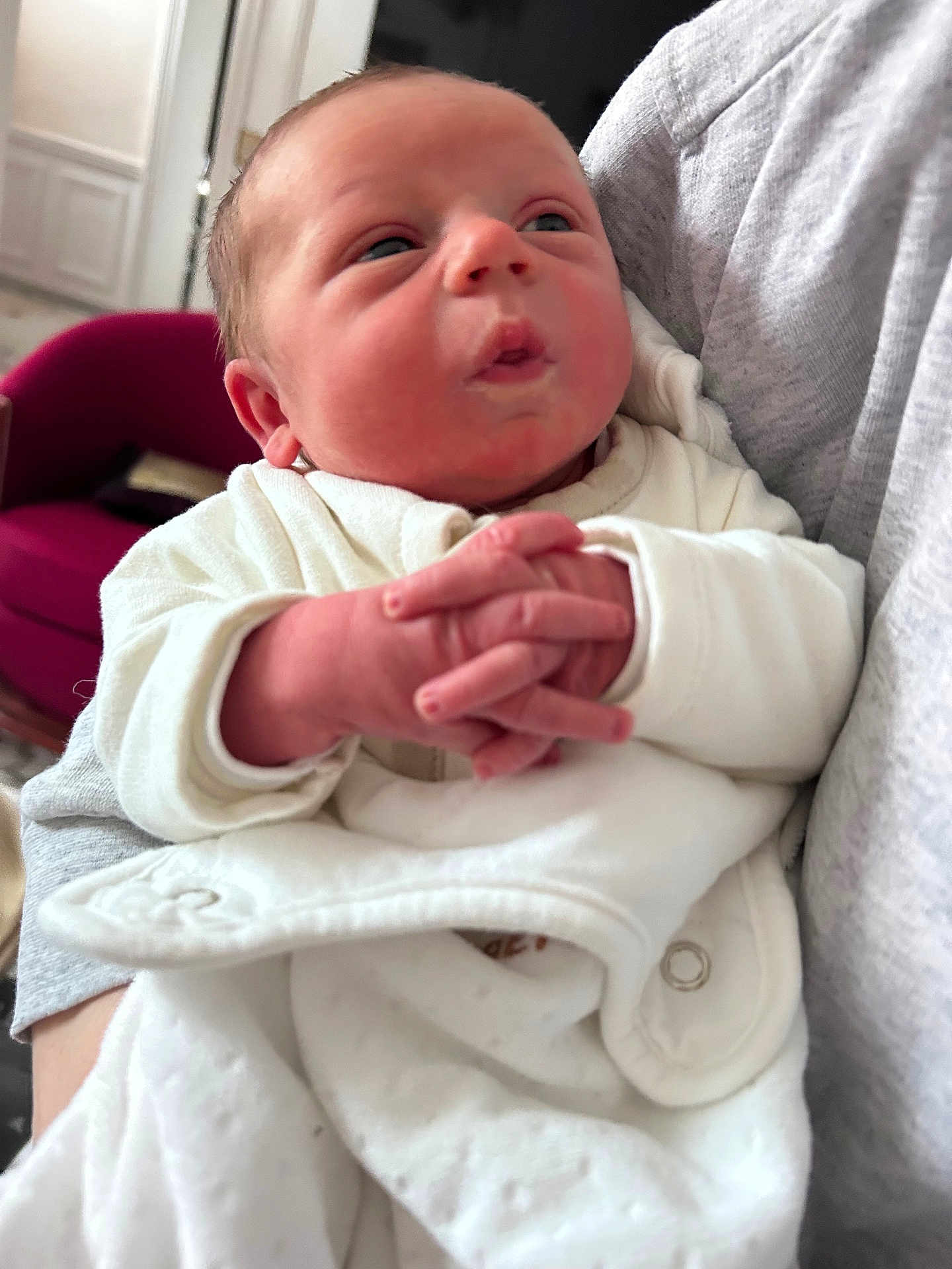 Liam participe au concours pour gagner de l'argent avec cette photo : baby, infant, newborn, hands, clothing, white_outfit, person, indoor, cradled, face, expression, red_chair, cozy, soft_lighting, portrait, close_up, human, cute, child, warm
