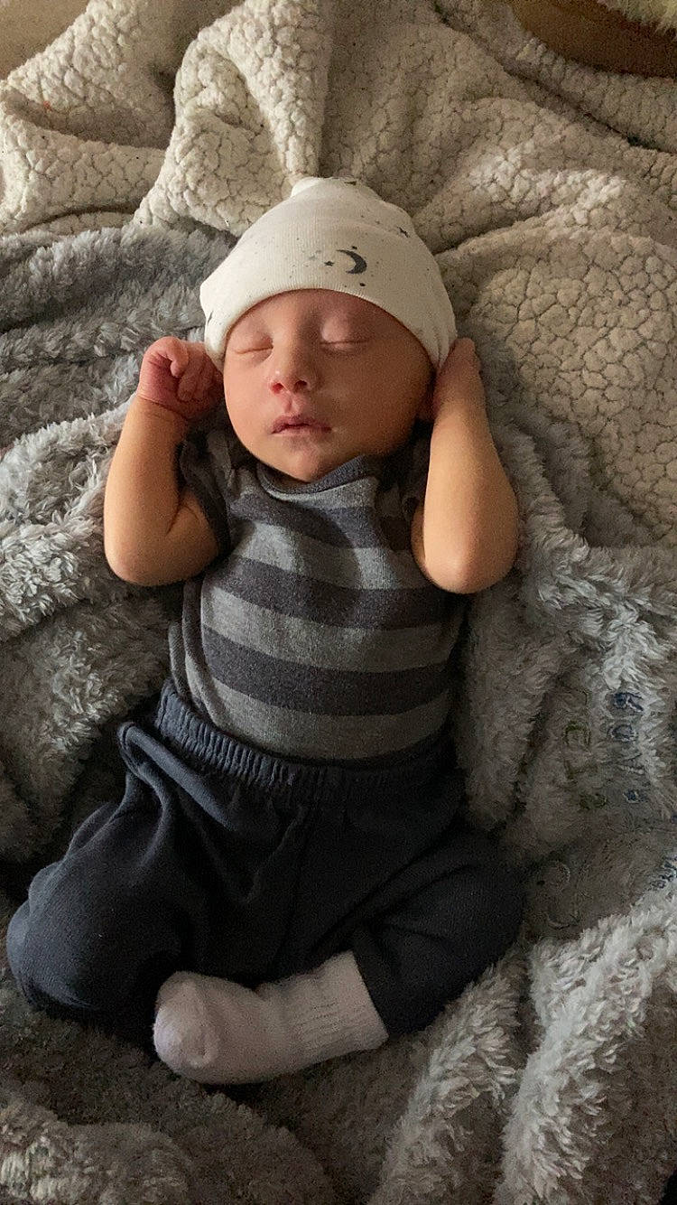 Oliver is registered to the contest to win money with this photo: baby, baby_toddler_clothing, cap, child, comfort, eye, flash_photography, grey, hand, head, headwear, human_body, leg, lip, organ, person, skin, sleeve, t_shirt, textile