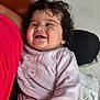 baby, child, smiling, curly_hair, pink_clothing, bunny_design, person, red_shirt, blanket, indoor, happy, cuddling, cute, toddler, cozy, face, portrait, infant, soft_texture, warm