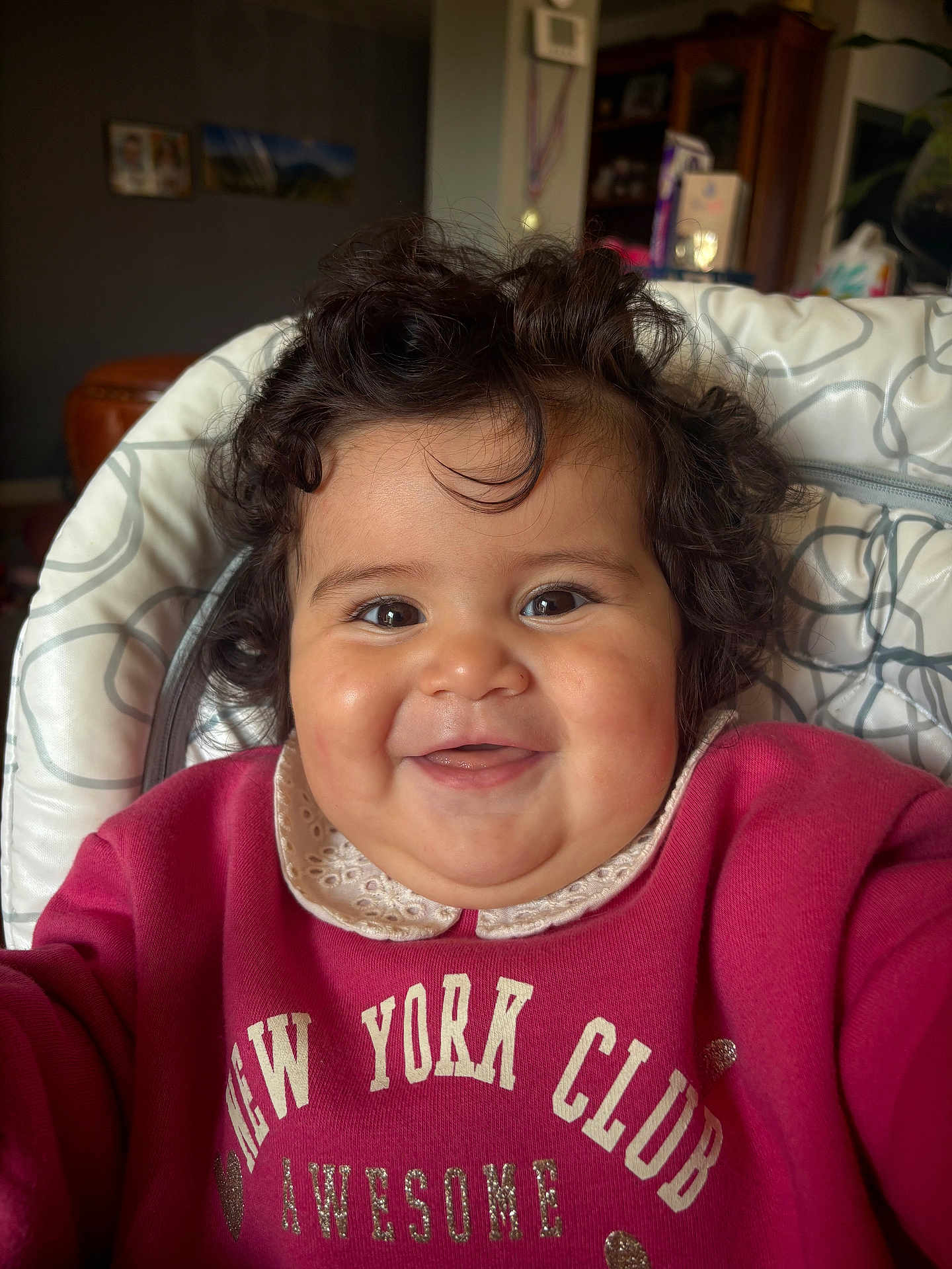 Blanca Lucia a rejoint le concours — aidez-le/la à gagner de superbes lots ! baby, child, smiling, curly_hair, red_sweatshirt, high_chair, indoor, portrait, face, happy, cute, cozy, clothing, person, infant, home, young_child, sitting, closeup, expression