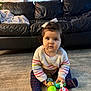 blanket, bow, carpet, child, colorful, couch, curly_hair, cute, floor, furniture, home, indoor, keys, knitwear, person, play, sitting, sweater, toddler, toy