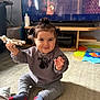 animation, baby, carpet, child, clothing, cute, face, floor, furniture, hair, home, indoor, person, pigtails, playful, sitting, smiling, socks, television, toy