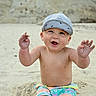 Levi is registered to the contest to win money with this photo: toddler, child, beach, sand, cap, shorts, smile, happy, bare_chest, summer, outdoor, playful, cute, sunny, sitting, young_child, joyful, fun, hands_up, casual_clothing