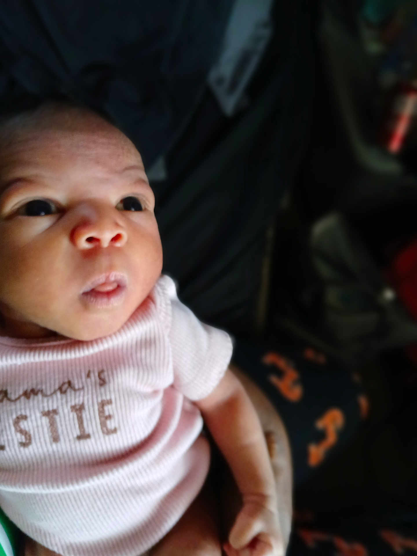 Armani joined the competition — help win amazing prizes! baby, infant, person, face, clothing, pink_shirt, hand, eyes, portrait, cute, expression, skin, newborn, holding, human, indoor, blurred_background, patterned_pants, soft_light, closeup