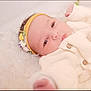 baby, newborn, infant, headband, flower_headband, blanket, knit_sweater, buttons, soft_texture, portrait, close_up, eyes, cheeks, hand, lying_down, cozy, plush, fur_rug, sleepy, skin