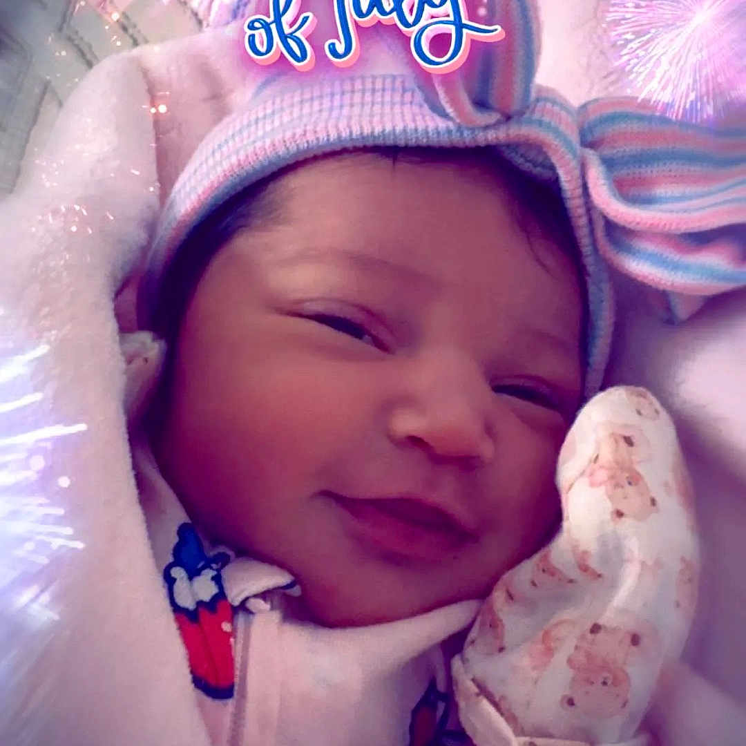 Madeline joined the competition — help win amazing prizes! newborn, baby, blanket, mittens, hat, smile, face, portrait, indoor, cute, infant, clothing, teddy_bear_pattern, celebration, fireworks, text_overlay, holiday, 4th_of_july, cozy, closeup