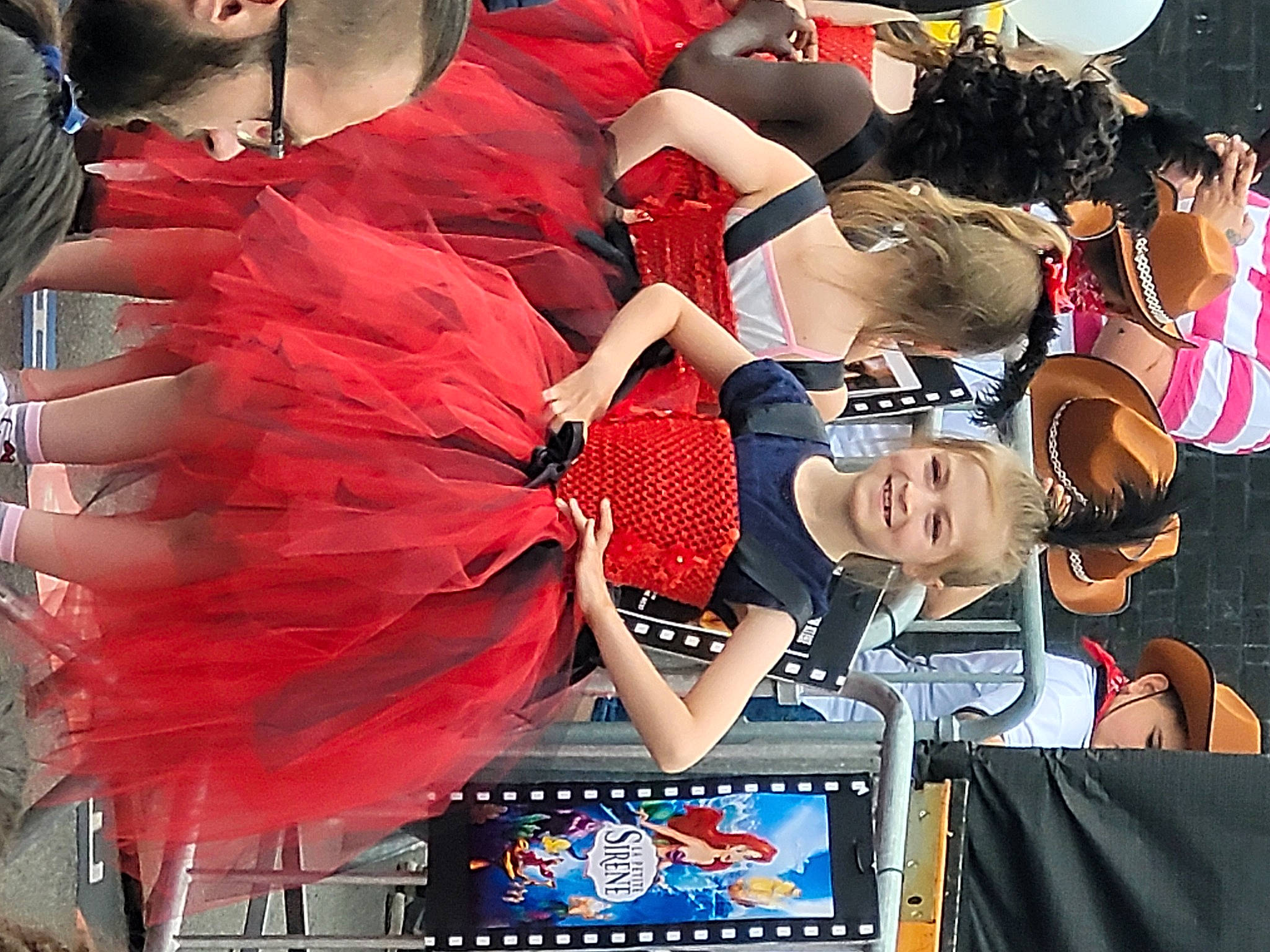 Juliana participe au concours pour gagner de l'argent avec cette photo : carmine, cheerleading, costume, crowd, dress, event, eyewear, fan, fashion_accessory, fashion_design, fun, hat, joy, person, product, public_event, sportswear, stage_equipment, sunglasses, t_shirt