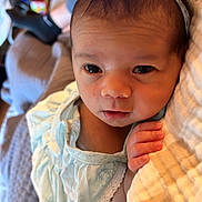 Esme is registered to the contest to win money with this photo: baby, infant, child, headband, blue_bow, blue_dress, blanket, hand, face, eyes, indoor, person, laptop, sock, legs, soft_texture, curious, resting, cozy, home