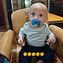 Léon participe au concours pour gagner de l'argent avec cette photo : baby, pacifier, high_chair, indoor, child, wooden_chair, blue_eyes, long_sleeve_shirt, pants, table, furniture, curious, seated, infant, human, face, head, room, lighting, casual