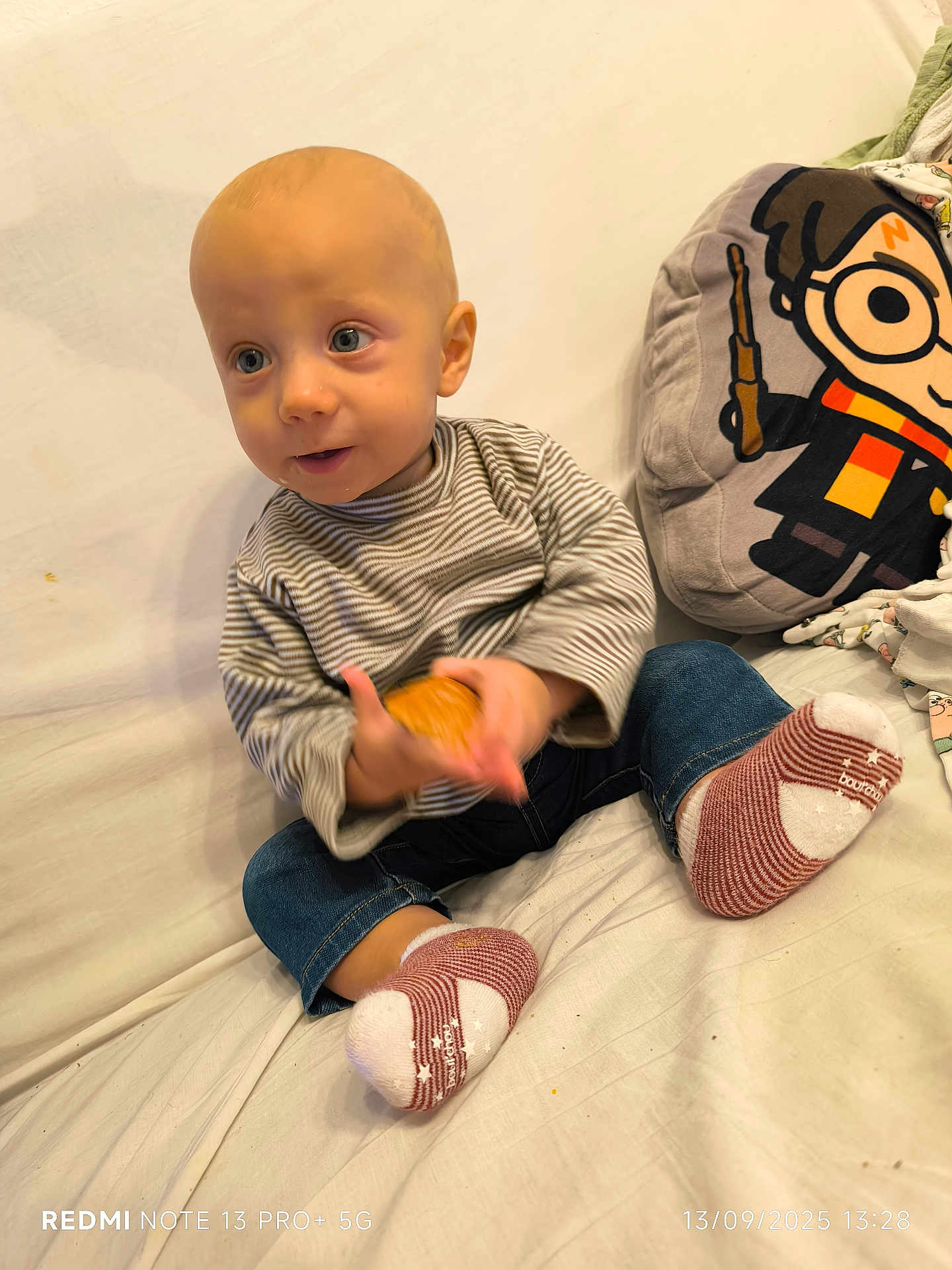 Léon participe au concours pour gagner de l'argent avec cette photo : baby, child, sitting, cookie, striped_shirt, striped_socks, couch, white_background, plush_pillow, cartoon_character, glasses, lightning_bolt, jeans, indoor, cute, curious, holding, clothing, footwear, portrait
