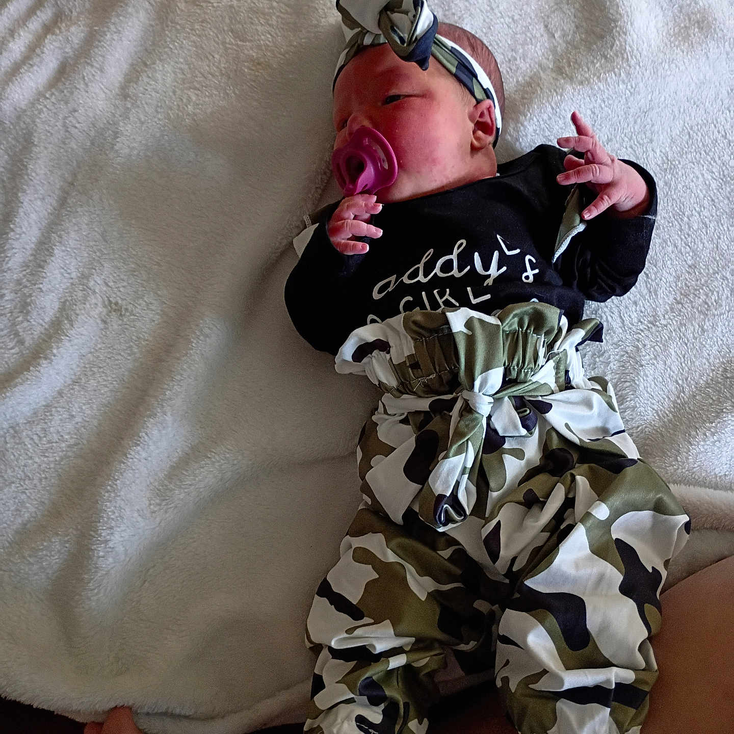 Lila joined the competition — help win amazing prizes! baby, baby_accessory, camo_pants, child, clothing, cute, fabric, foot, hand, headband, indoors, infant, lying_down, newborn, pacifier, person, resting, sleepwear, soft_texture, white_blanket