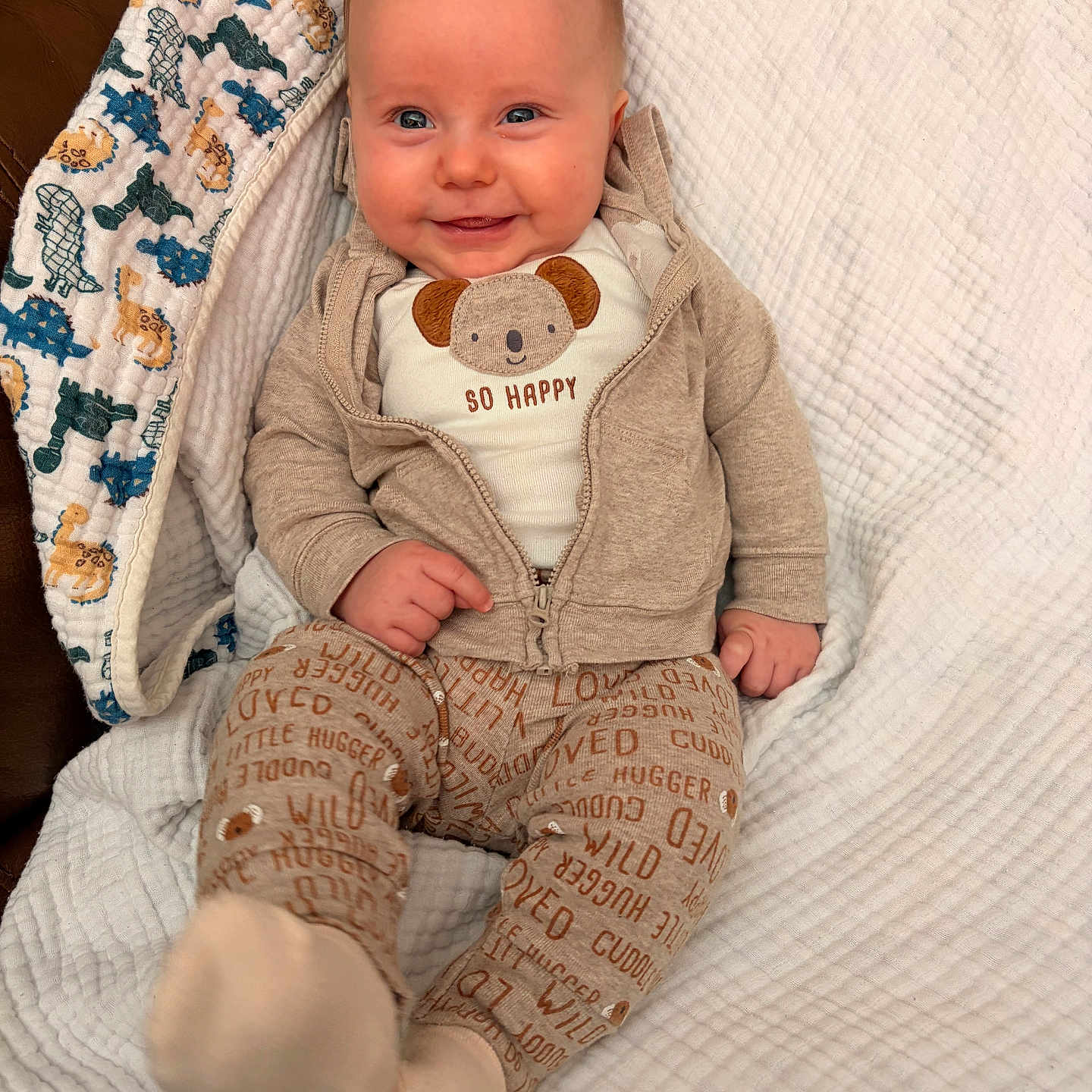 Lorenzo is registered to the contest to win money with this photo: animal_print, baby, beige, blanket, blue, cozy, cute, eyes, fabric_pattern, face, feet, hands, hoodie, infant, onesie, pajamas, portrait, sitting, smiling, soft_texture