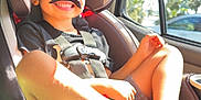Conrad is registered to the contest to win money with this photo: child, boy, car_seat, seat_belt, fake_mustache, smile, happy, sunlight, car_interior, window, legs, cup_holder, portrait, toddler, hair, clothing, safety_harness, automobile, rear_window, seat