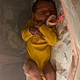 newborn, baby, sleeping, crib, yellow_onesie, pacifier, infant, bed, blanket, legs, feet, peaceful, cozy, indoor, soft_lighting, child, resting, cute, person, nursery