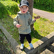 Tiziano a rejoint le concours — aidez-le/la à gagner de superbes lots ! toddler, child, cap, jacket, rock, snack, tree, outdoor, greenery, concrete, pathway, sunlight, grass, pants, shoes, curious, standing, nature, daytime, casual