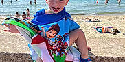 Tiziano a rejoint le concours — aidez-le/la à gagner de superbes lots ! child, boy, towel, beach, sea, water, sand, sunlight, smile, happy, footwear, sandal, outdoor, summer, vacation, playful, shore, sunbather, sky, portrait