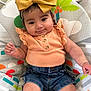 baby, child, infant, smiling, headband, bow, clothing, peach_top, denim_shorts, sitting, baby_seat, colorful, indoor, cute, portrait, happy, young_child, person, closeup, comfortable