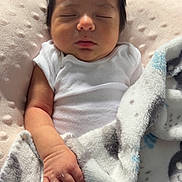 Dylan is registered to the contest to win money with this photo: baby, sleeping, blanket, cushion, infant, soft_texture, white_clothing, cozy, peaceful, resting, child, portrait, indoor, newborn, human, cute, relaxing, toddler, hand, face