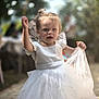child, toddler, white_dress, tulle, outdoor, party, blurred_background, smiling, happy, cute, little_girl, celebration, sunlight, pavement, person, fashion, portrait, dress_up, fun, innocence