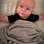 baby, infant, blanket, striped_sheet, lying_down, smiling, arms_outstretched, cozy, indoor, soft_lighting, cute, wrapped, child, person, face, head, skin, comfort, bed, resting
