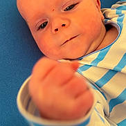 Noah joined the competition — help win amazing prizes! baby, infant, child, face, hand, fist, blue_background, striped_clothing, closeup, portrait, cute, soft_skin, lying_down, young_child, apparel, baby_clothes, young_infant, person, human, indoor