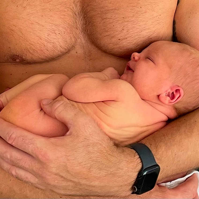 Ozzi is registered to the contest to win money with this photo: arms, baby, care, chest, closeup, hands, human, infant, love, naked, newborn, person, protection, skin, sleeping, smartwatch, smile, torso, watch, wrinkles