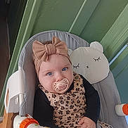 Joy a rejoint le concours — aidez-le/la à gagner de superbes lots ! baby, baby_chair, black_sleeves, blue_eyes, bow, child, closeup, cute, face, green_wall, hand, headband, indoor, infant, pacifier, patterned_clothing, portrait, seated, soft_toys, toy_bar