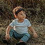 child, toddler, sitting, grass, outdoor, nature, casual_clothing, white_tshirt, jeans, brown_shoes, greenery, sunlight, portrait, cute, young_child, boy, natural_light, expression, daytime, relaxed