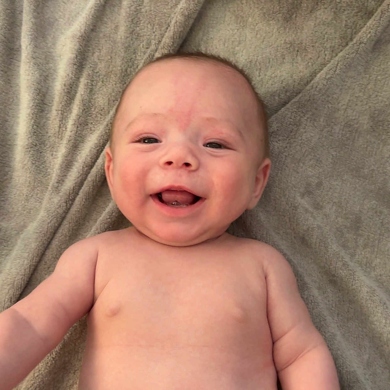 Eli is registered to the contest to win money with this photo: baby, blanket, cheerful, child, close_up, cute, expression, face, happy, human, indoors, infant, joy, lying_down, natural_light, newborn, skin, smiling, soft_texture, warm