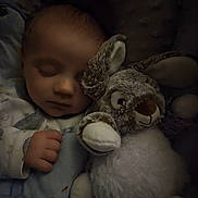 Théo participe au concours pour gagner de l'argent avec cette photo : baby, sleeping, stuffed_animal, bunny, plush_toy, cozy, dark, soft, child, peaceful, cuddle, infant, cute, hand, blanket, pajamas, closeup, indoors, rest, quiet