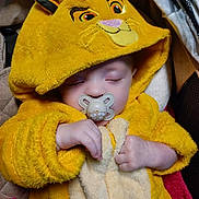 Théo participe au concours pour gagner de l'argent avec cette photo : adorable, baby, blanket, child, closed_eyes, clothing, cozy, cute, hands, indoor, infant, lion_hood, pacifier, plush, resting, sleeping, soft_fabric, toddler, warm, yellow_costume