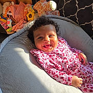 Wrenleigh joined the competition — help win amazing prizes! baby, smiling, curly_hair, pink_clothing, leopard_print, plush_toy, giraffe, cushion, soft_texture, infant, happy, indoors, child, face, portrait, baby_toys, blanket, cozy, playful, relaxed