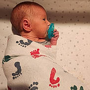 Spencer joined the competition — help win amazing prizes! newborn, baby, pacifier, blanket, footprint_pattern, swaddled, infant, side_profile, sleeping, soft_lighting, cozy, star_pattern, bed, cute, small_hand, wrapped, peaceful, human, child, indoors