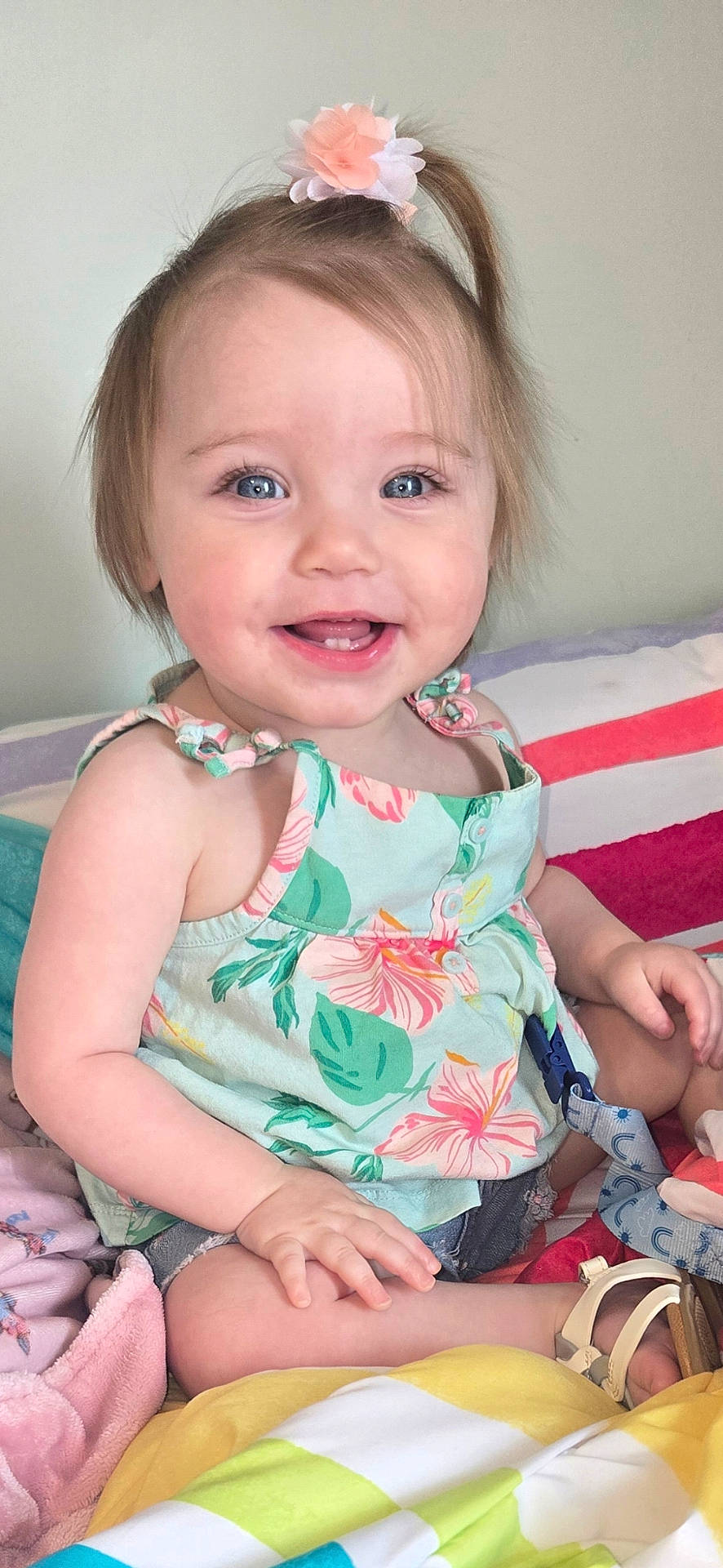Brendalyn is registered to the contest to win money with this photo: baby, blanket, blue_eyes, child, closeup, cute, floral_dress, hair_bow, hand, happy, indoor, nursery, pillow, portrait, sandal, sitting, skin, smiling, teeth, toddler