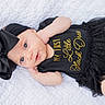 baby, infant, black_dress, headband, bow, blanket, laying_down, cute, portrait, child, fashion, sparkle, white_background, clothing, newborn, soft_light, smiling, skin, baby_girl, closeup