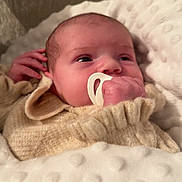 Leyana a rejoint le concours — aidez-le/la à gagner de superbes lots ! baby, infant, newborn, pacifier, hand, face, eyes, blanket, textured_blanket, knitted_sweater, cozy, pillow, closeup, portrait, star_pattern, heart_emoji, overlay_bar, indoor, resting, soft_lighting