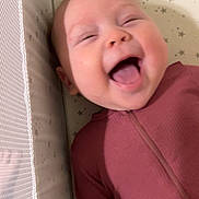 Sophia is registered to the contest to win money with this photo: baby, laughing, crib, stars, onesie, infant, happy, child, smiling, sleepwear, face, closeup, cute, indoors, soft_lighting, pattern, mesh, baby_crib, person, joy