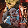 baby, infant, nasal_tube, oxygen_tube, medical_tape, outdoor, grass, blanket, adult, holding, love, family, care, sunlight, warm_light, closeup, head, face, skin, person