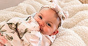Esmae is registered to the contest to win money with this photo: baby, infant, smiling, face, headband, bow, blanket, floral, pattern, wrapped, cozy, knit, texture, cute, portrait, child, person, indoor, soft, happy