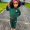 Khrystlyn joined the competition — help win amazing prizes! child, girl, portrait, outdoor, driveway, suburban, house, car, curly_hair, headband, green_outfit, tracksuit, flower_design, boots, peace_sign, pouting, smiling, standing, grass, pavement
